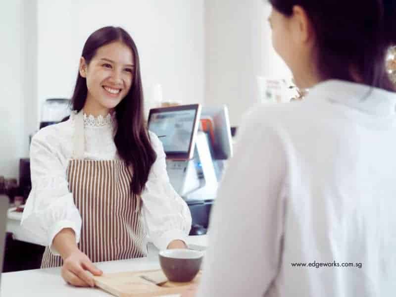A lady serving a customer, with custom pos systems at the counter