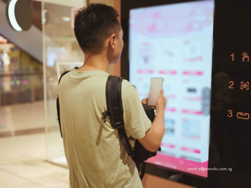 An image of a man standing in front of a retail self-checkout kiosk