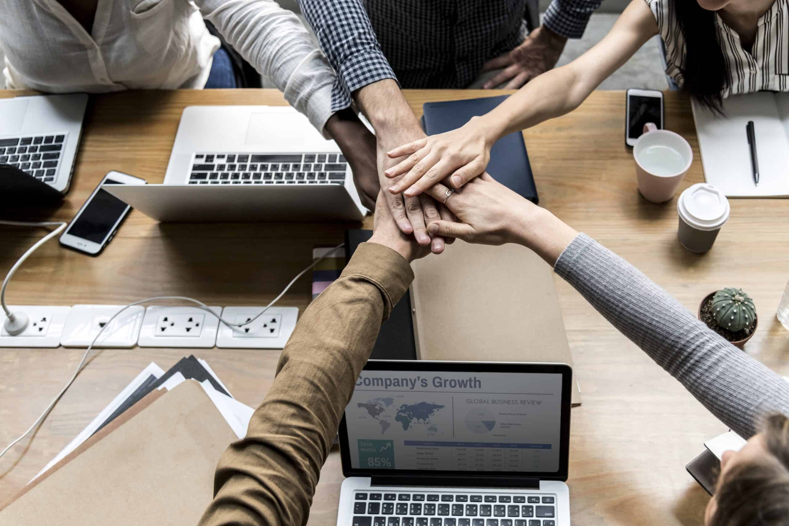 A unified team of business people stacking hands, symbolizing Edgeworks Solutions' mission to build an edge through strong partnerships, community involvement, and a dedicated staff.