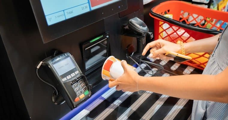Person scanning groceries at the self service checkout kiosk counter
